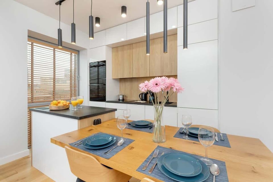 Stylish dining area with a wooden table, elegant tableware, and soft pendant lighting.
