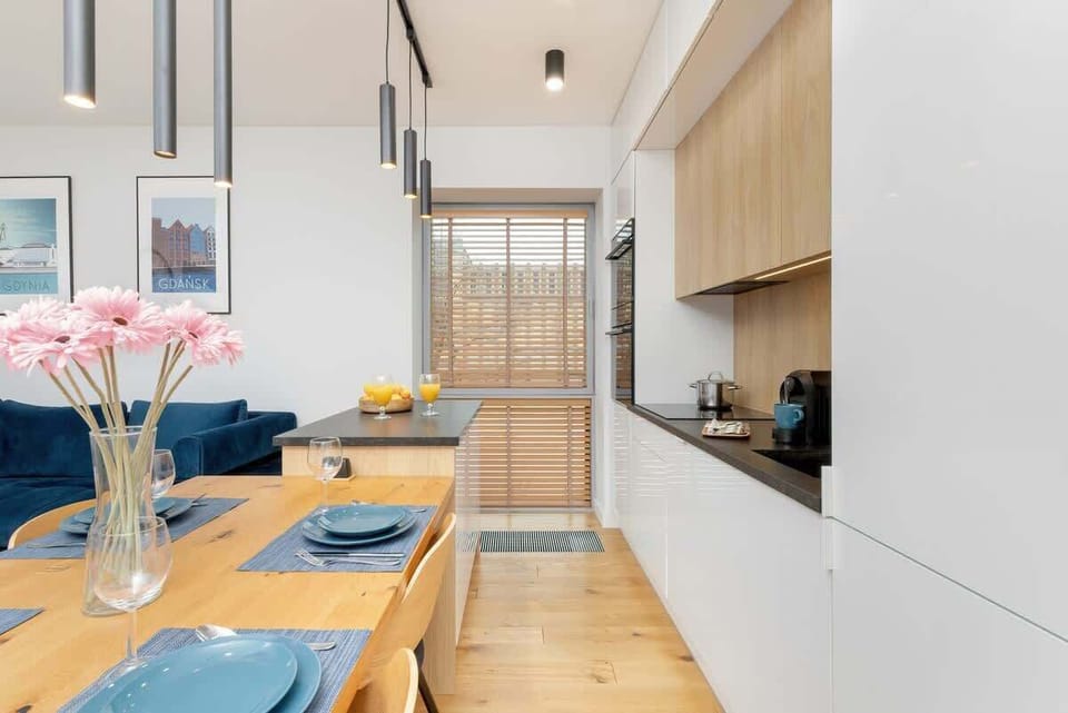 Open-concept kitchen and dining space with natural wood tones, modern decor, and fresh flowers.
