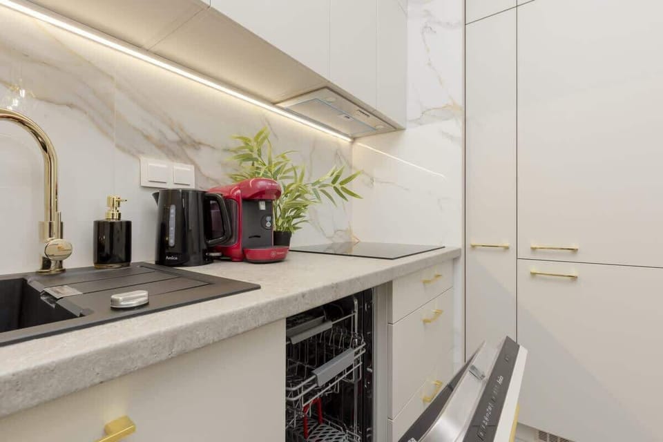 Sleek kitchen countertop with a built-in stovetop, potted greenery, and modern appliances.
