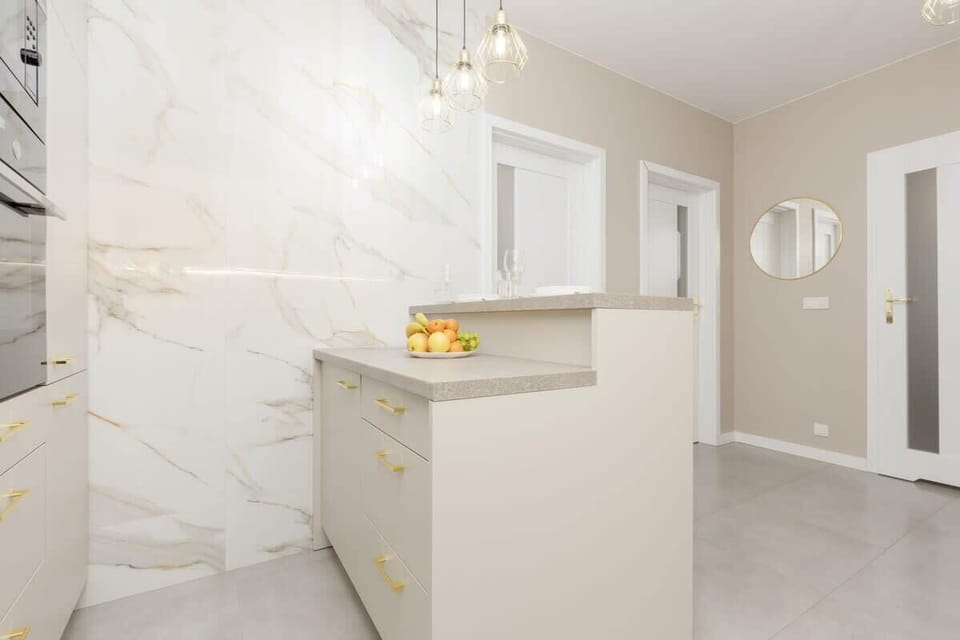 Spacious hallway with marble-style flooring, leading to an elegant kitchen and dining area.
