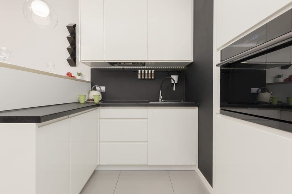 Modern kitchen with sleek white cabinetry, black countertops, and under-cabinet lighting.
