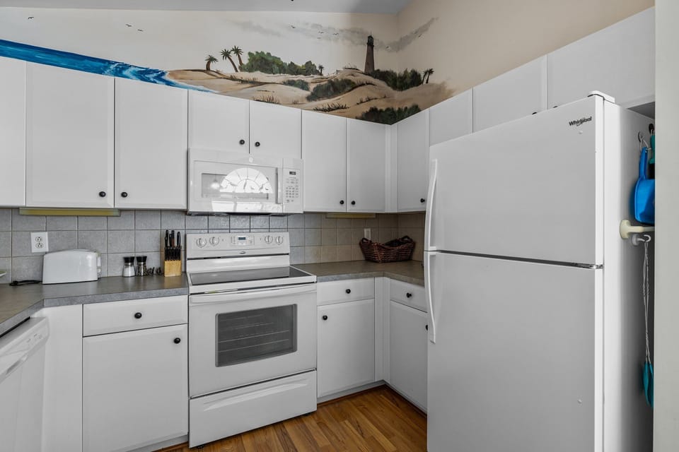 Your fully equipped kitchen features everything needed for home cooking, with a charming coastal mural adding artistic flair to your culinary adventures.
