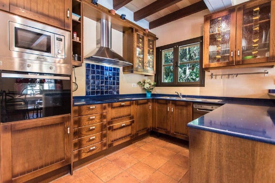Fully equipped kitchen at Villa Gabriela featuring wooden cabinetry, spacious countertops, oven, microwave, dishwasher and natural light.