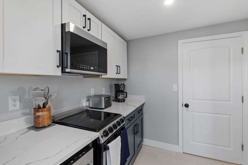 Kitchen with coffee maker, toaster, microwave, oven, and stove.