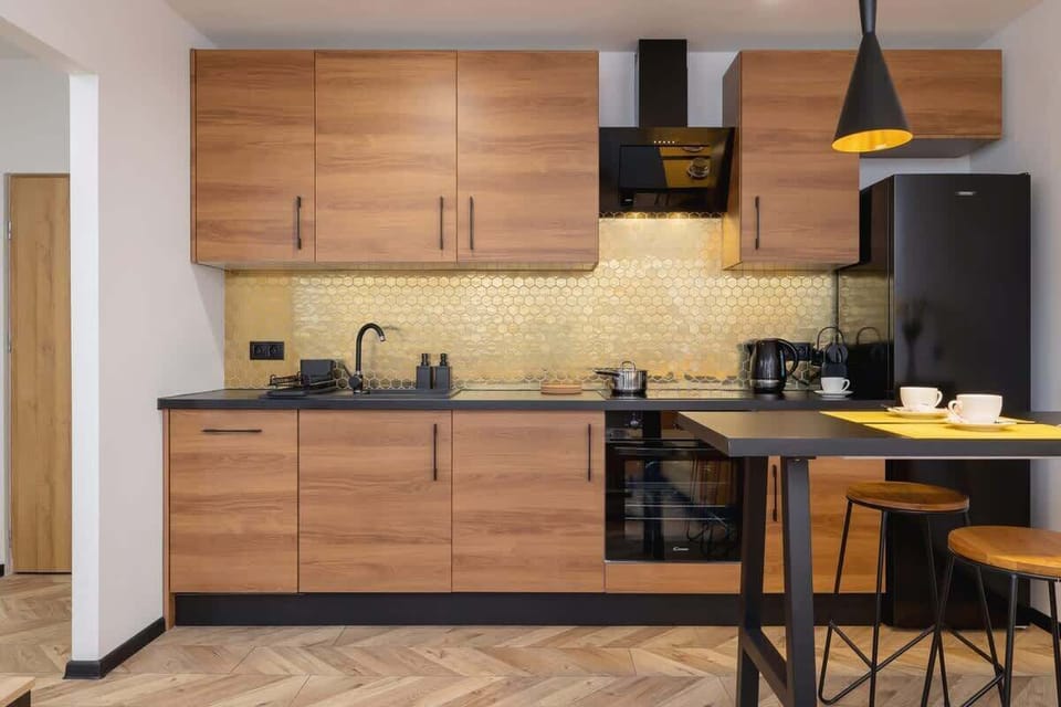 The modern kitchen with warm wooden cabinetry, black appliances, and a glossy yellow backsplash, creating a stylish and functional cooking space.
