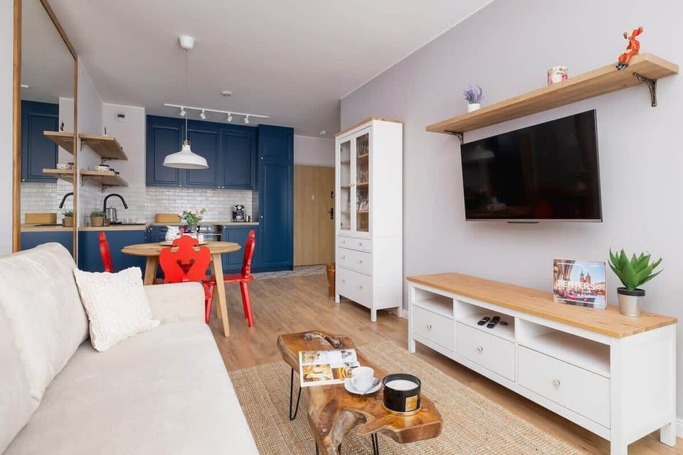A spacious and stylish living area with a TV console, floating shelves, and a mix of modern and rustic decor elements.

