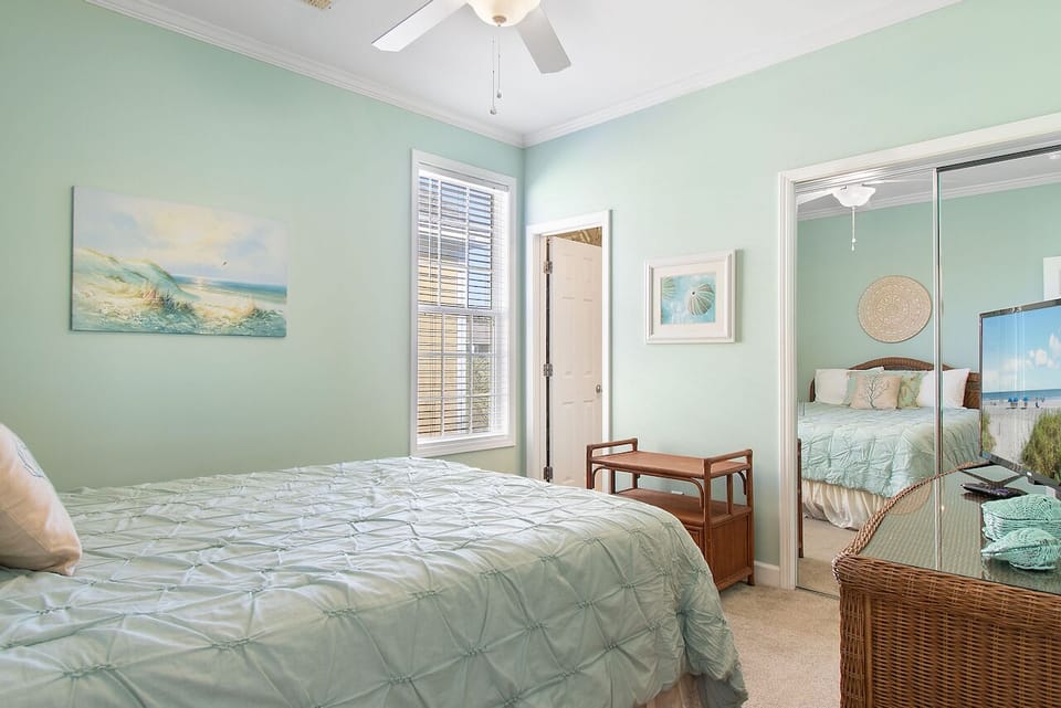 Your peaceful bedroom sanctuary features soft mint walls and ocean-inspired artwork, creating the perfect coastal retreat for restful nights.