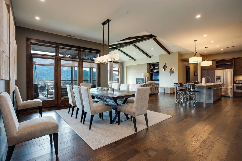 Gather around this elegant dining table with mountain vistas streaming through floor-to-ceiling windows, creating the perfect setting for memorable meals.