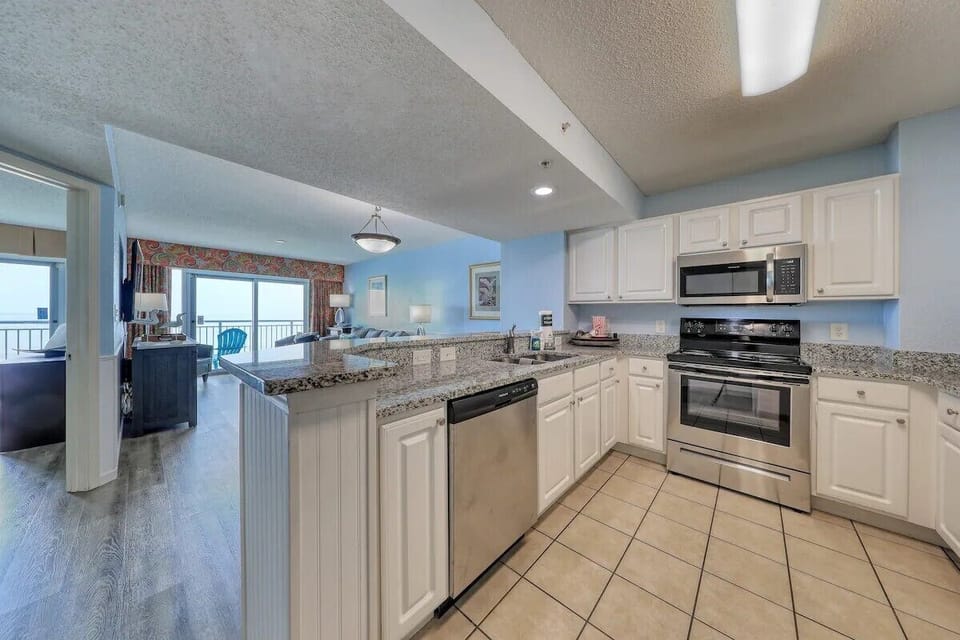 Modern kitchen with granite counters, stainless appliances, and ocean view.