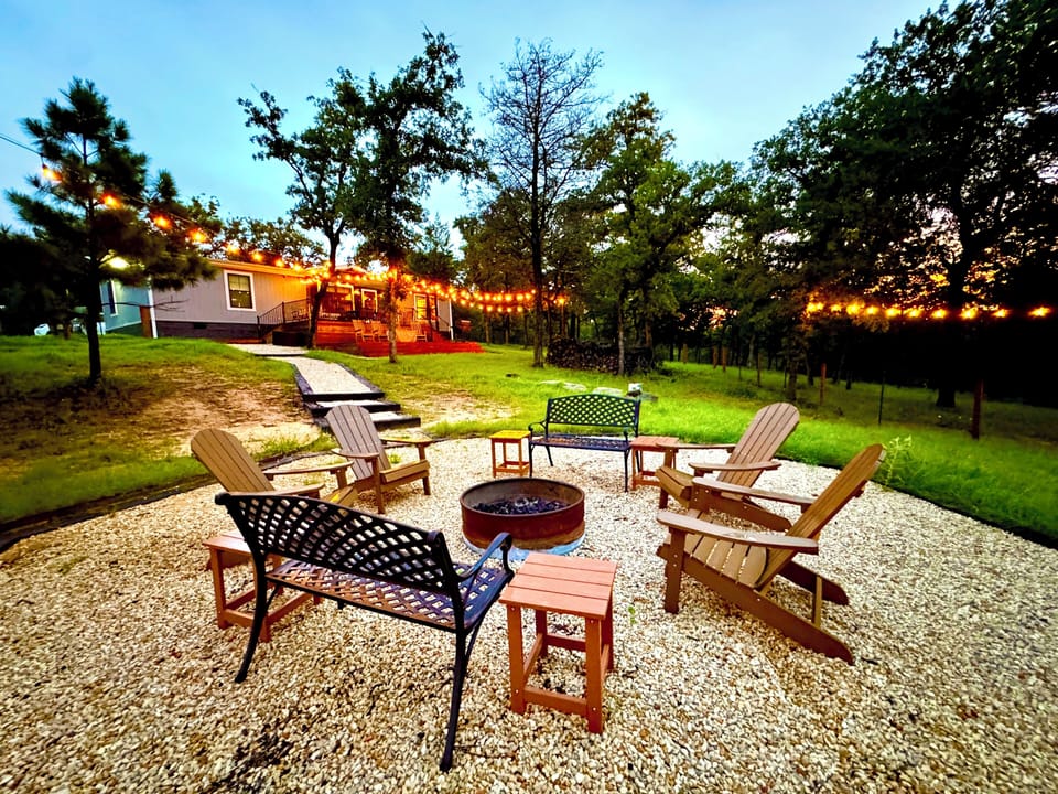 Fire pit with benches and adirondack chairs. Stocked with firewood.