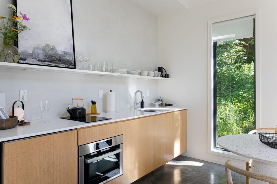 Modern kitchen equipped with fridge, 2 burner induction stove, microwave/convection oven, olive oil, pots and pans, spices, french press, and more. 