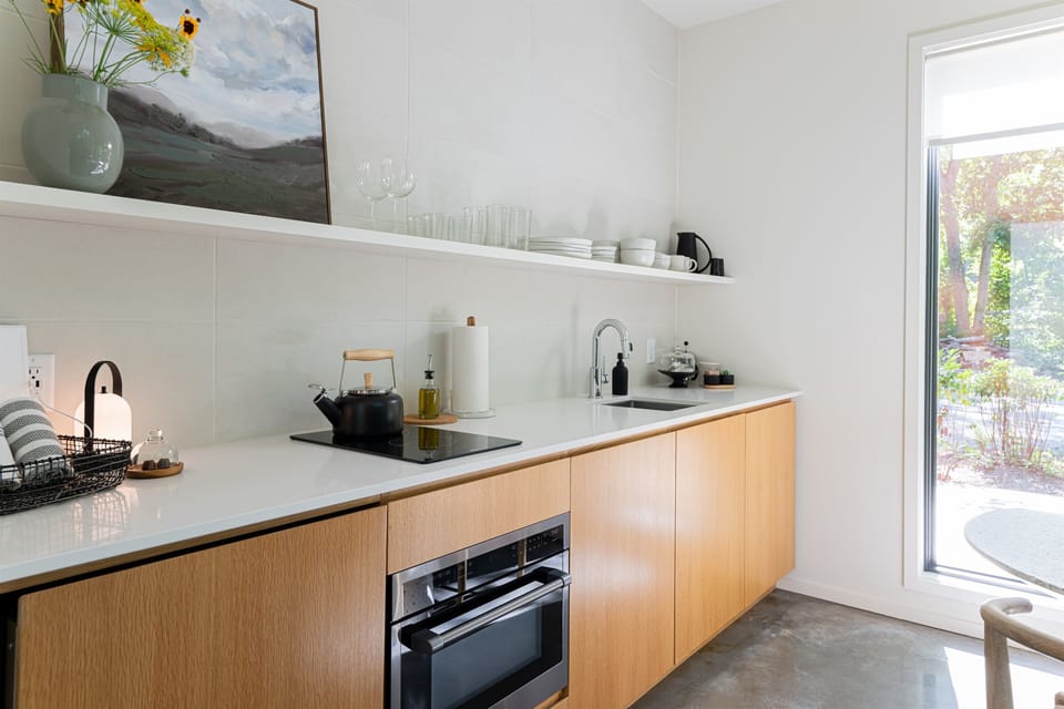 Modern kitchen equipped with fridge, 2 burner induction stove, microwave/convection oven, olive oil, spices, pots and pans, french press and more.