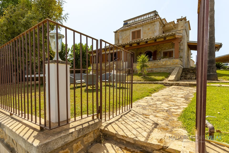 Exterior access to Villa Alejandra with stone pathway, private garden and traditional Mallorcan-style façade in a peaceful setting.