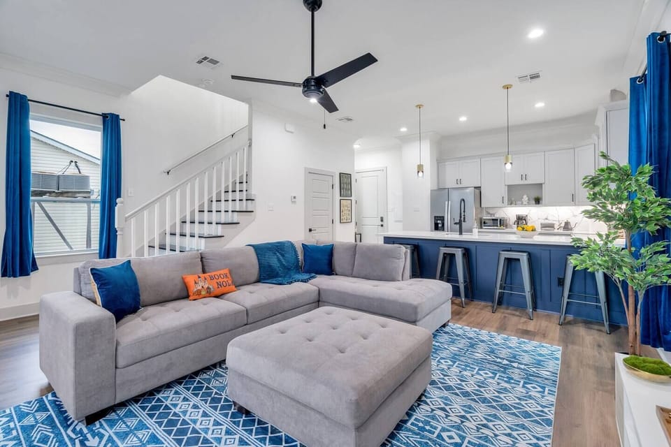 Bright living room w/ plush sectional, ceiling fan & bold blue accents.
