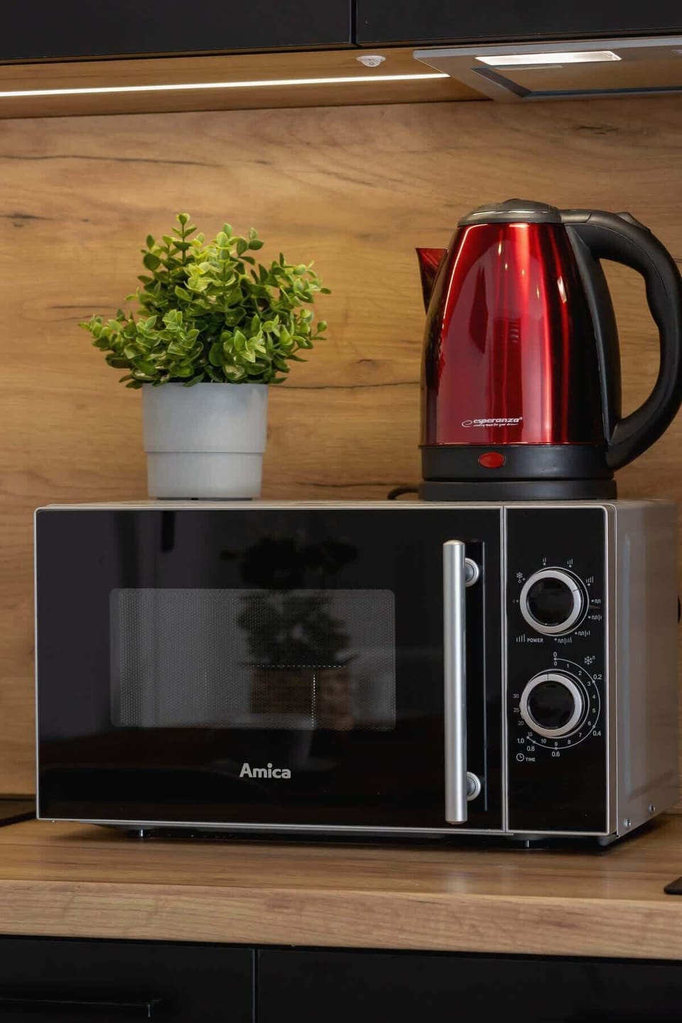 Another detailed view of the kitchen, emphasizing the wooden backsplash, integrated lighting, and a neatly arranged shelf with small appliances.
