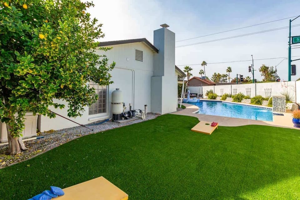 Private yard with sparkling pool, sun loungers, cornhole, and outdoor covered patio with BBQ grill.