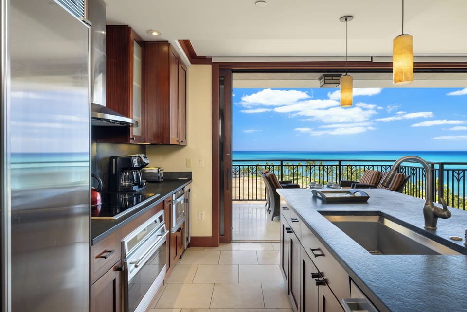 Your gourmet kitchen opens to breathtaking ocean views, where cooking becomes pure joy with azure waters stretching endlessly beyond your private balcony.