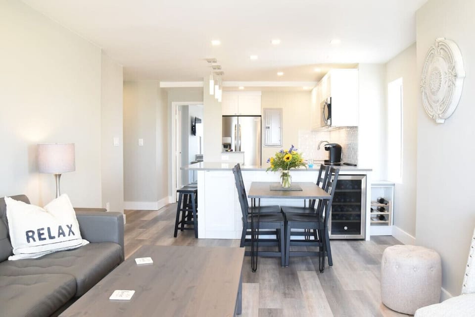 Modern coastal dining with an open-concept kitchen. Enjoy meals at the table, sip coffee at the breakfast bar, and unwind after beach days, bright, stylish, and made for relaxing together.