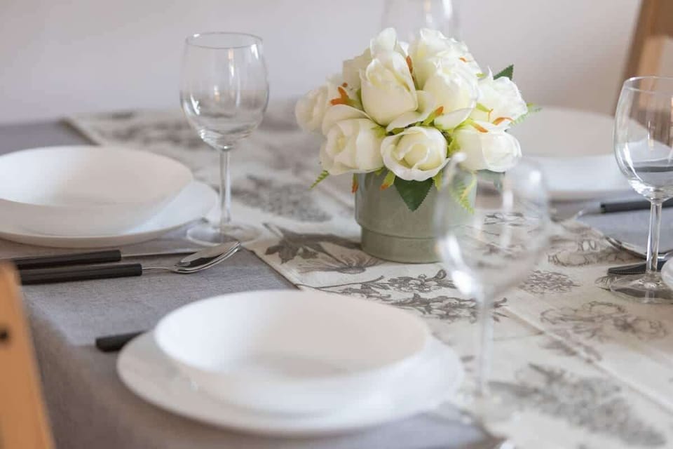 A beautifully set dining table with elegant white plates, delicate glassware, and a floral centerpiece, adding a touch of sophistication.

