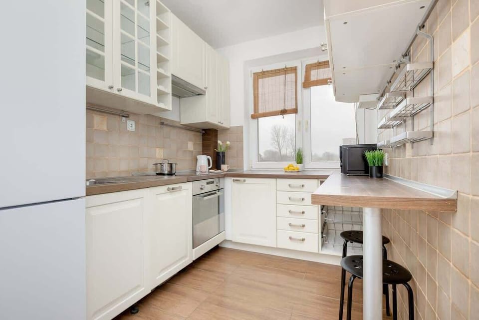 A bright and spacious kitchen with white cabinetry, a tiled backsplash, and wooden accents, offering a warm and inviting cooking space.


