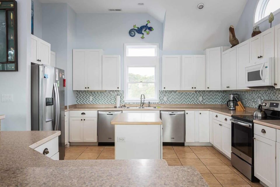 Fully Equipped Kitchen with Refrigerator, Stove, Oven, Microwave, Coffee Maker,Dishwasher and a Small Window that Brings in Natural Light.