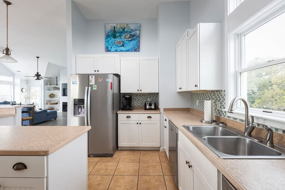 Fully Equipped Kitchen with Refrigerator, Stove, Oven, Microwave, Coffee Maker,Dishwasher and a Small Window that Brings in Natural Light.