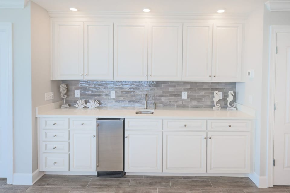 Retrieve chilled drinks from the compact fridge and admire seahorse decor against the glossy tile backsplash