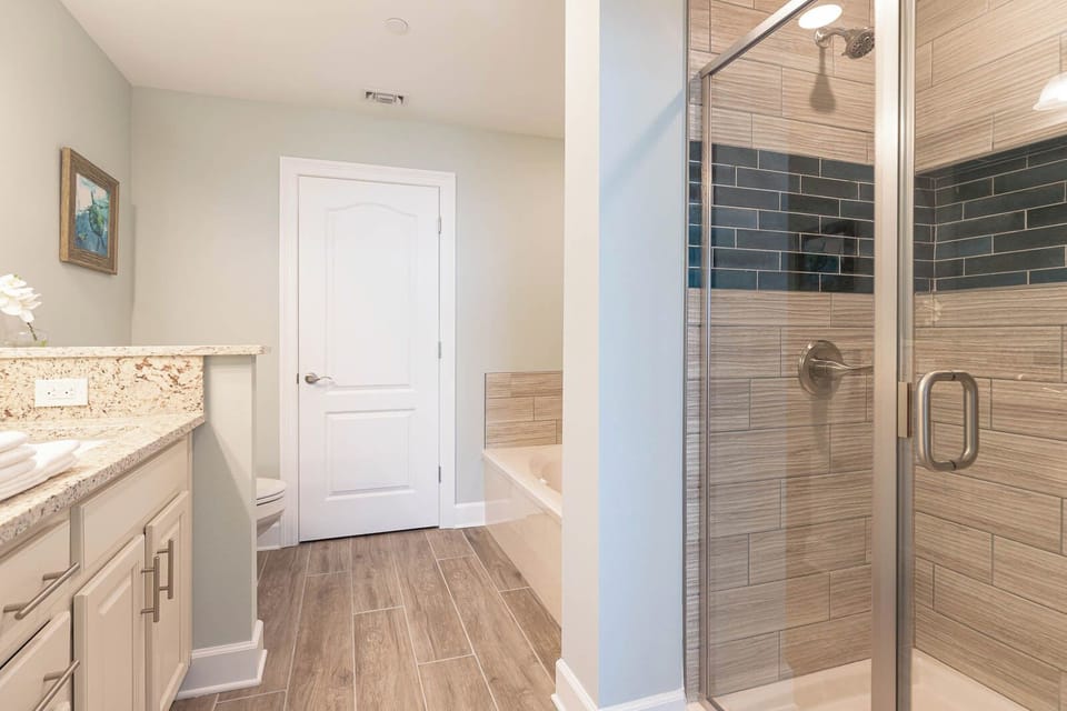 Soak in the soothing tub or admire the shower's dark horizontal tile accents in this elegant master bath