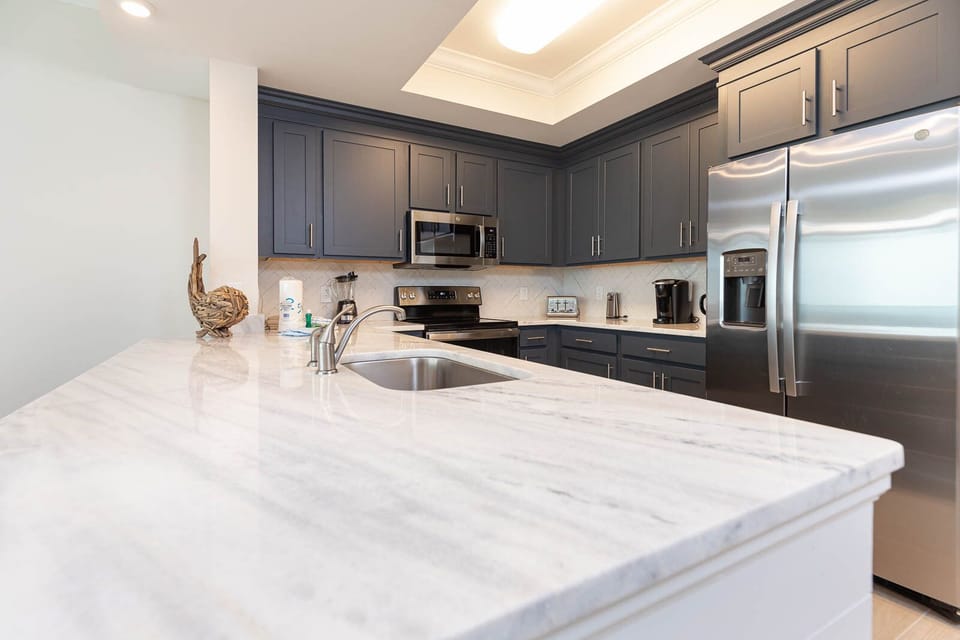 Brew your morning coffee at the marbled counter in this stylish kitchen with elegant cabinetry