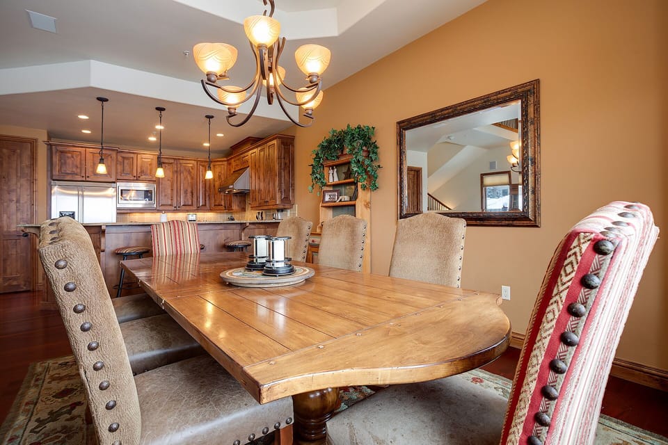Gather around this elegant wooden dining table where memorable meals and conversations await under the warm glow of the chandelier.