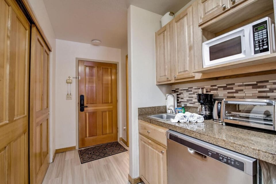 Small kitchenette with a toaster oven, microwave, coffee maker, dishwasher and sink