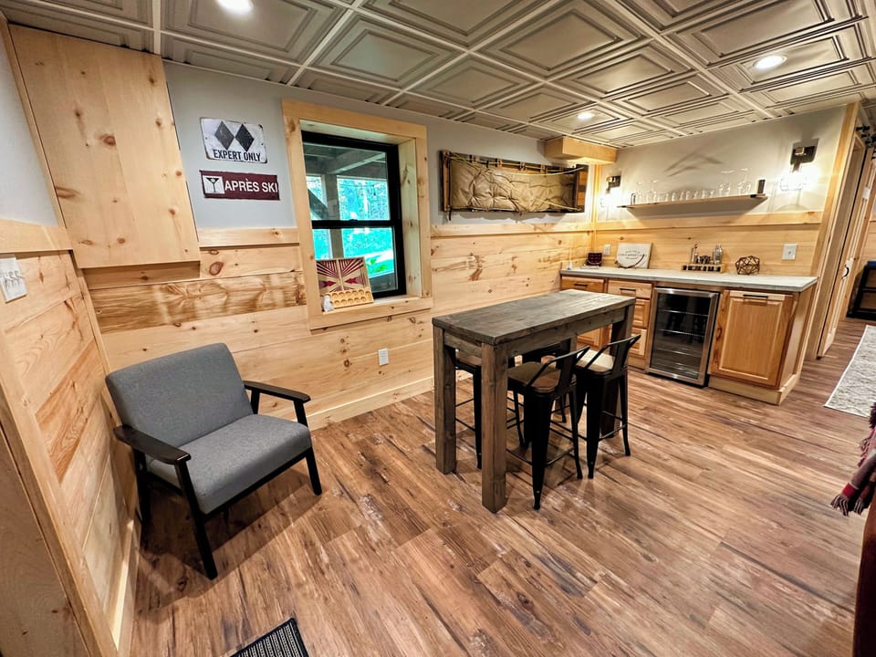 Lower level living space with pellet stove, TV, dry bar, and lower exit.