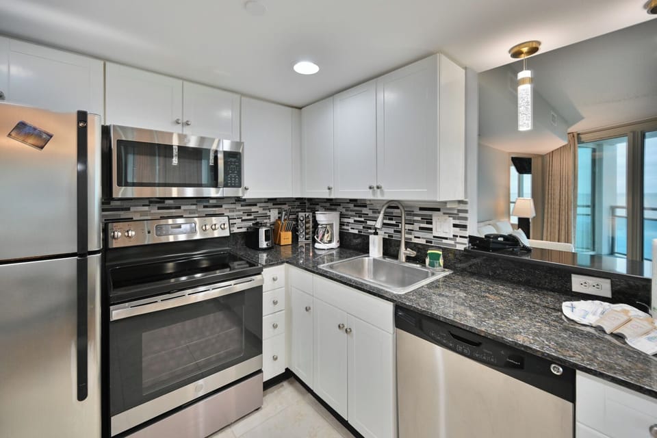 Modern kitchen with stainless, white cabinets, blue backsplash & breakfast bar