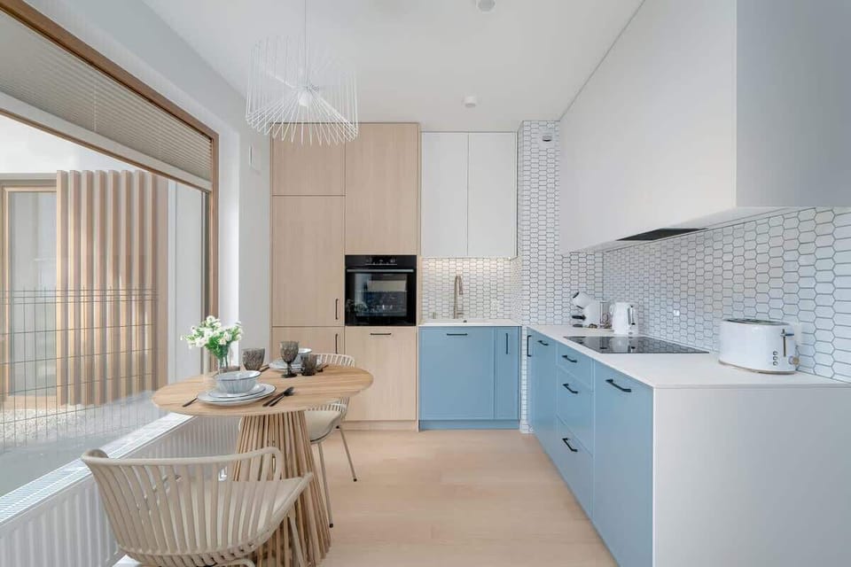A spacious kitchen with blue lower cabinets, white upper cabinets, and a tiled backsplash.

