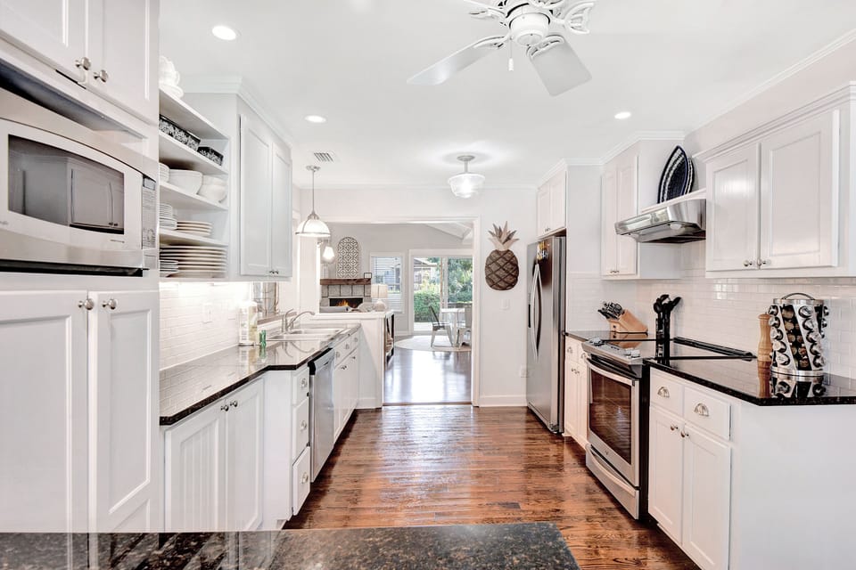 Main Kitchen With Stainless Appliances - Main kitchen with stainless appliances, granite counters, open shelving, and direct access to the dining room.