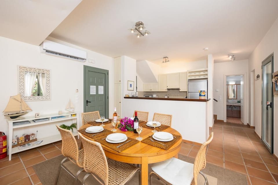 Open-plan living room with sofas, dining area, kitchen, A/C, WiFi internet, and satellite TV
