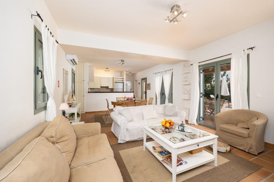 Open-plan living room with sofas, dining area, kitchen, A/C, WiFi internet, and satellite TV
