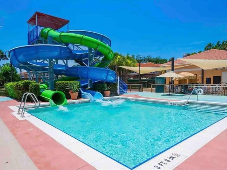Dive into fun with this vibrant pool area featuring a thrilling water slide and sparkling blue waters. The bright, sunny environment is perfect for relaxing on the surrounding loungers or enjoying a splash with family and friends.