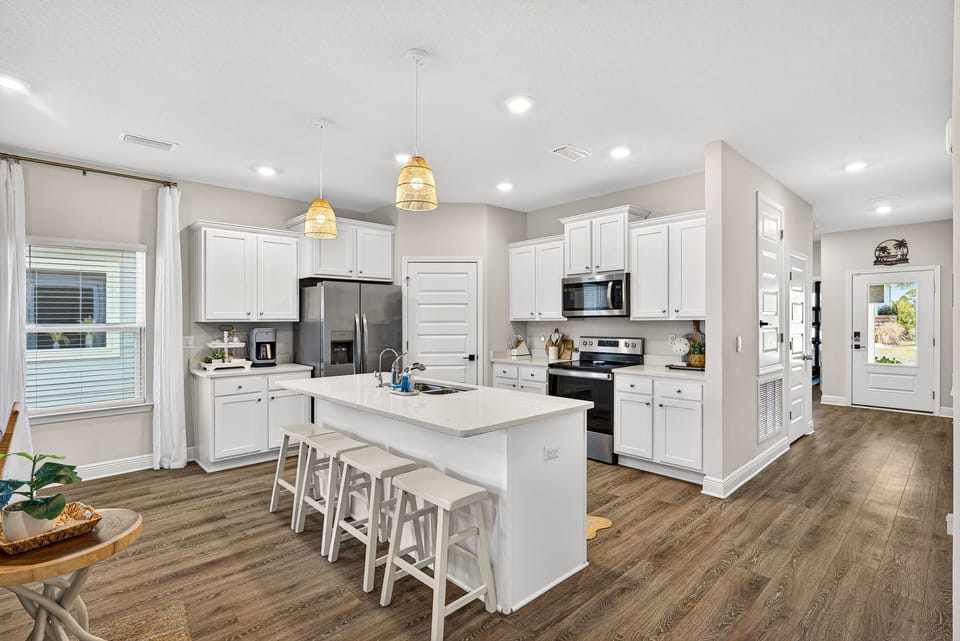 Prepare your favorite meals in this bright, modern kitchen featuring stainless steel appliances, ample counter space, and a large island perfect for gathering with family and friends.