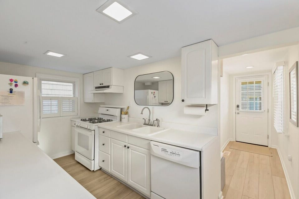Cook up a storm in our bright, fully equipped white kitchen! Features a gas range, dishwasher, and plenty of counter space. The clean design is perfect for quick meals or preparing a feast after a fun day at the beach. 