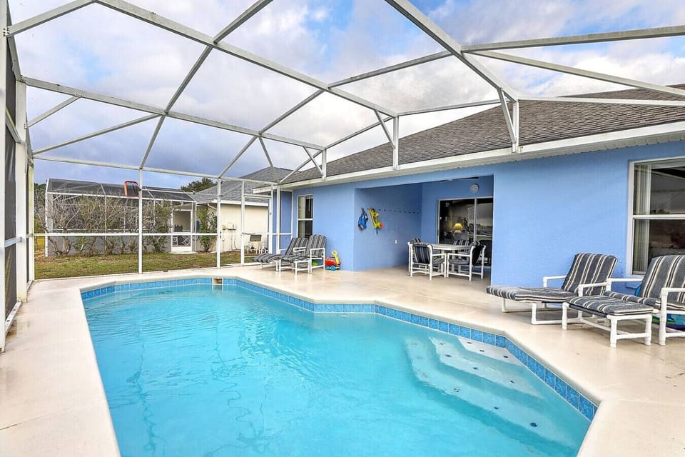 Private screened pool with covered lanai, outdoor dining, and lounge chairs — perfect for relaxing after a day at theme parks..