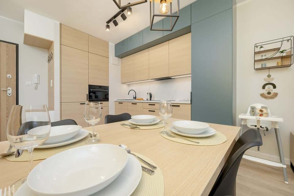 Kitchenette with a similar design to the previous one, with a light wood theme and white counter, but taken from a different angle.