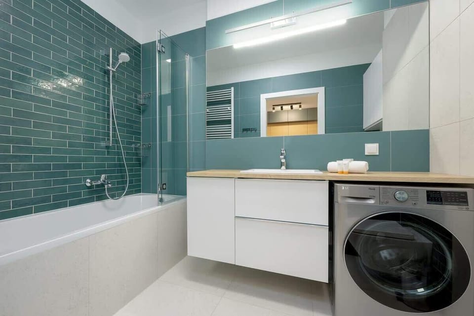 Bathroom with a similar teal and white color scheme, but showing more of the bathtub and a mirror above