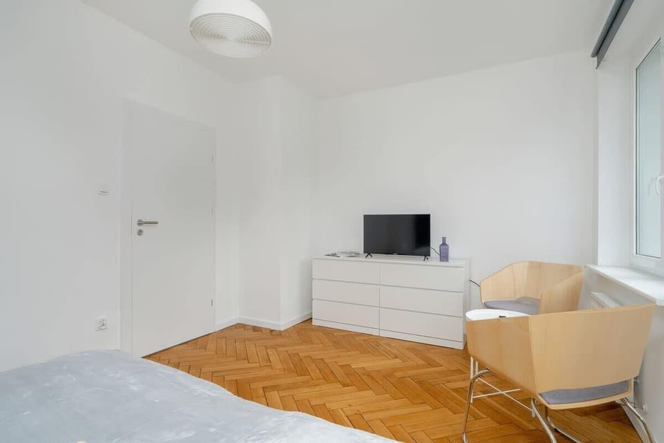 Another view of the living room, featuring a TV, a wooden floor, and a clean, minimalistic aesthetic.






