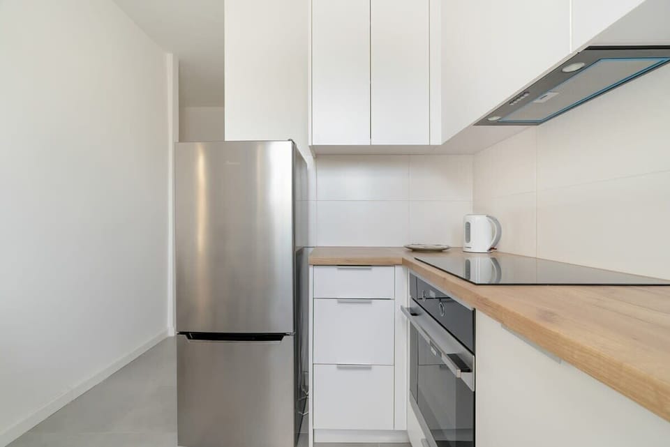 A kitchen corner with white cabinets, a stove, and a wooden countertop for a modern touch.
