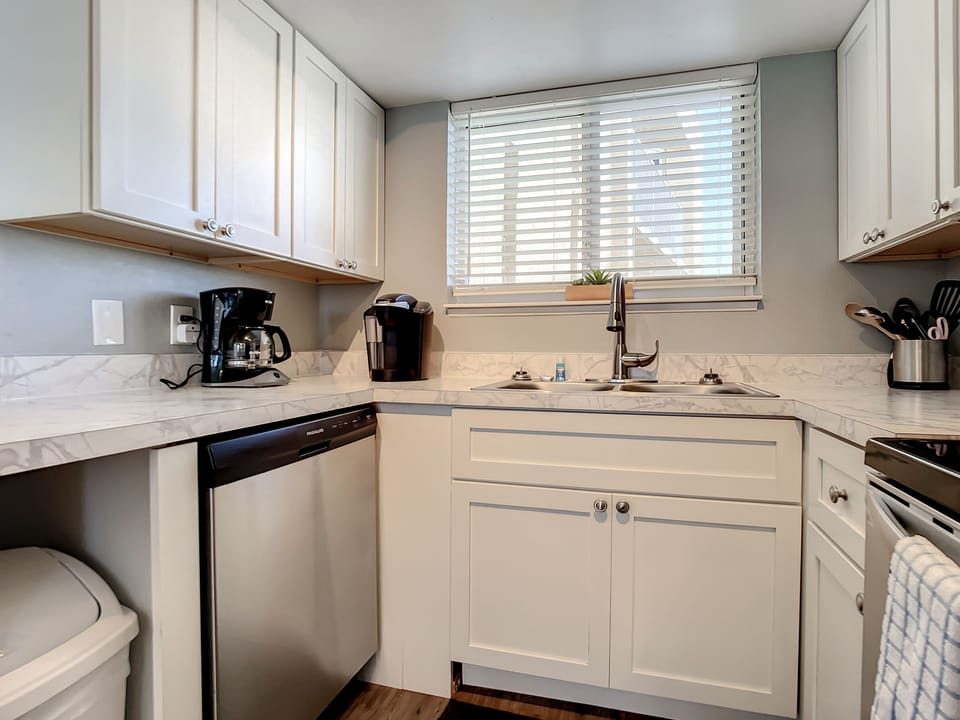 Bright and practical kitchen with white cabinetry, marble-style countertops, and modern appliances.