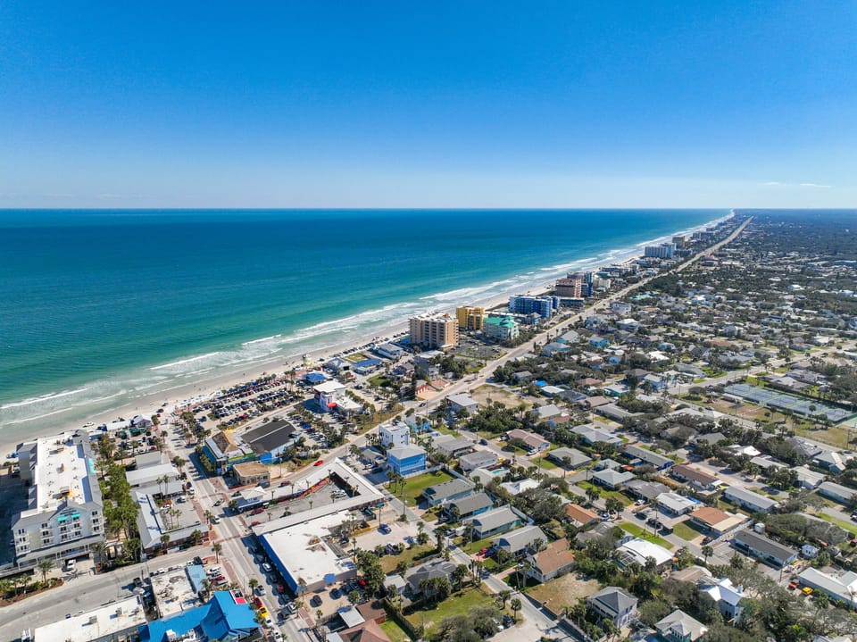 Aerial view showcasing vibrant beachfront communities and miles of picturesque shoreline under a clear blue sky.