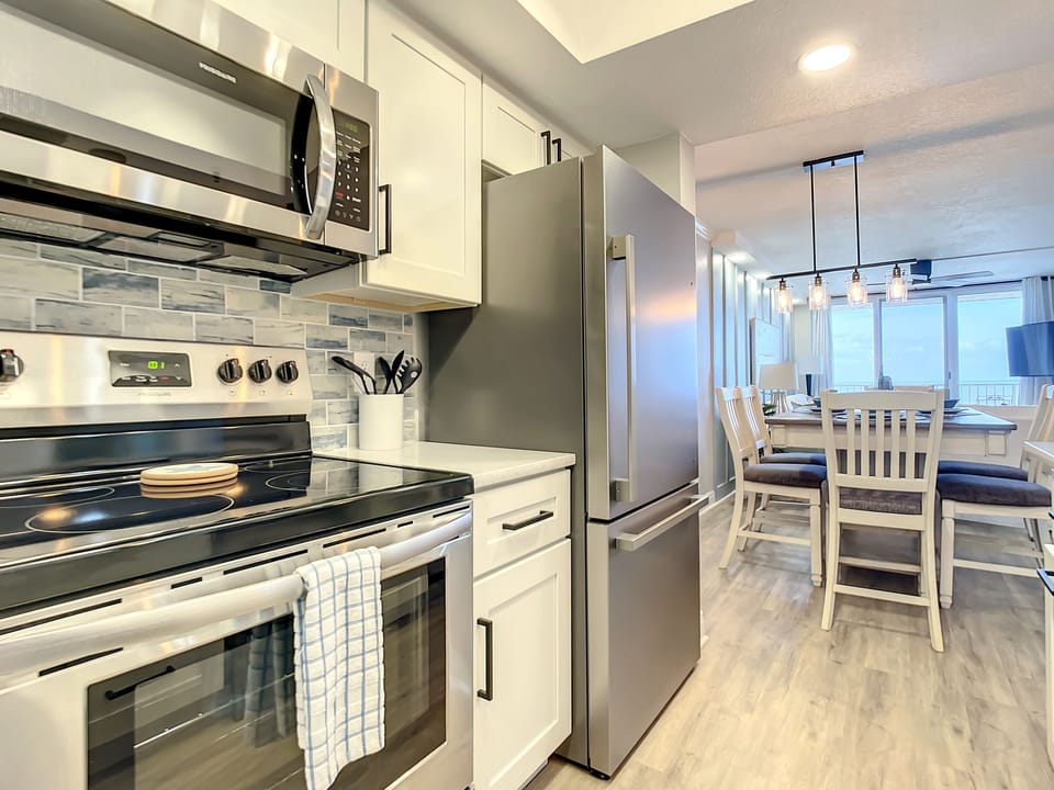 Fully equipped kitchen with stainless steel appliances, sleek backsplash, and a bright, open layout.