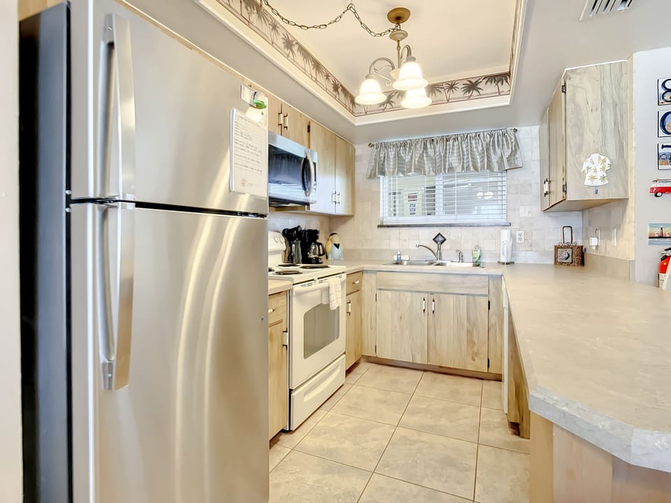 Spacious kitchen featuring modern appliances, ample counter space, and a tropical backsplash.