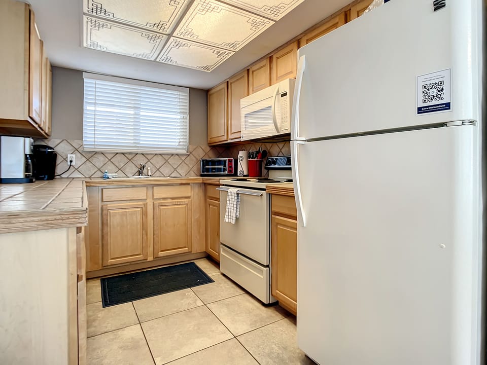 Functional kitchen with all the essentials, featuring a stove, refrigerator, and ample counter space.